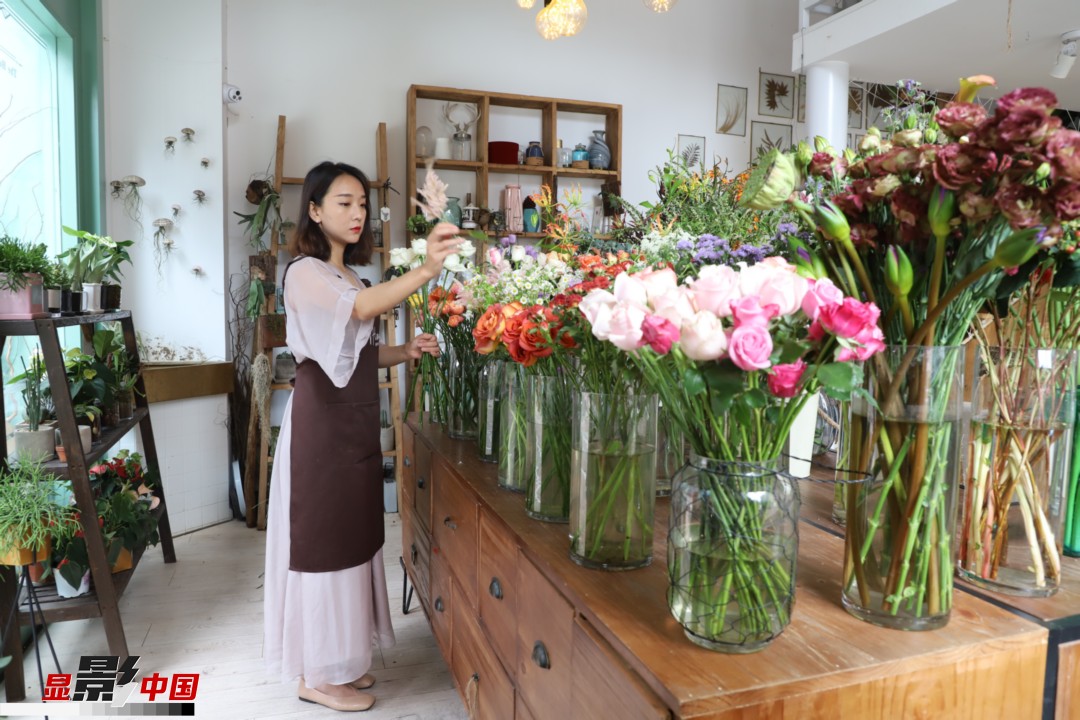 王黎媛是一名河南姑娘，在昆明念完大學(xué)后，就再也舍不下春城的藍(lán)天陽光、青山碧水，更舍不下這里的四時繁花，于是就干脆留了下來，成了一名媒體人。2017年的時候又毅然辭去工作，創(chuàng)業(yè)開起了花店，成了都市里的一名“花房姑娘”。圖為王黎媛在自己的花店中整理鮮花。新華網(wǎng) 周亞平/攝 念新洪/文